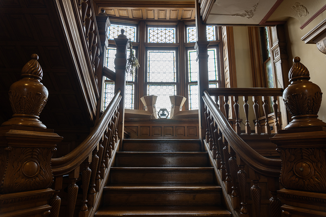 Looking up wooden steps leading to a large window and "The Translation Machine", an interactive sound sculpture by artist Daric Gill.