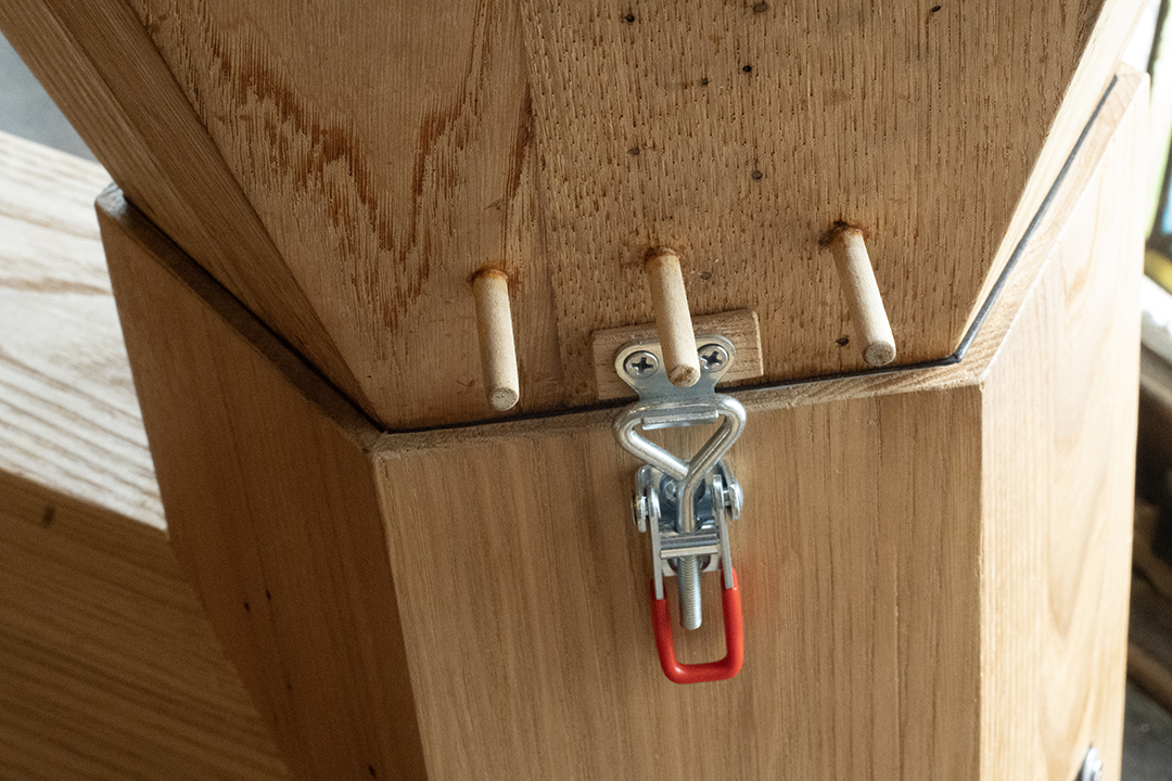 A red handled clasp holds together the two wooden halves of an interactive sound sculpture.