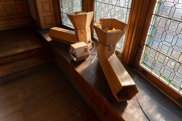 Two stylized acoustic speaker boxes create a 'V' shape on a window bench in a mansion.